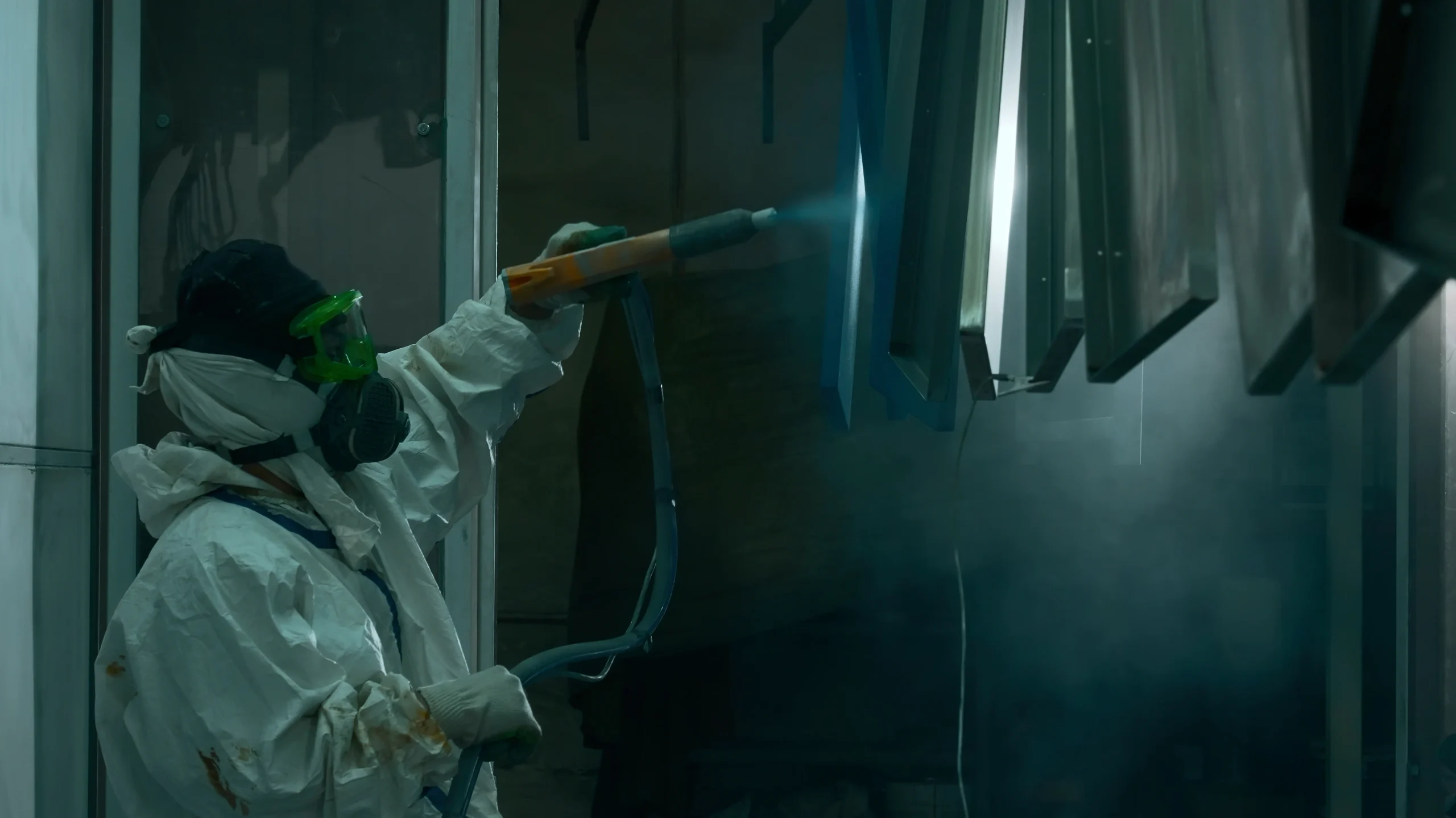 Home Worker applying powder coating to a metal part with a spray gun